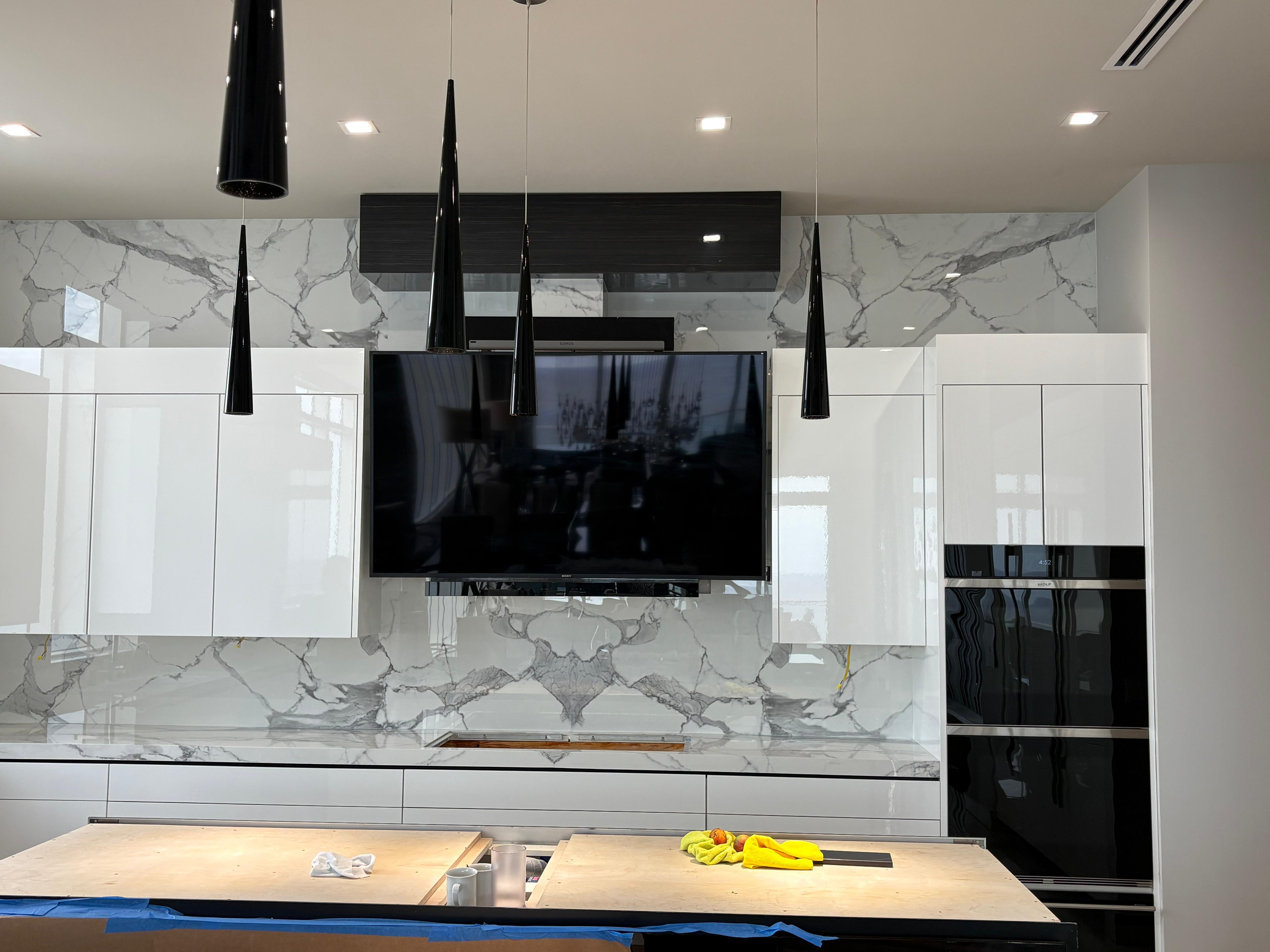 Book-matched Calacatta porcelain backsplash with white gloss cabinetry