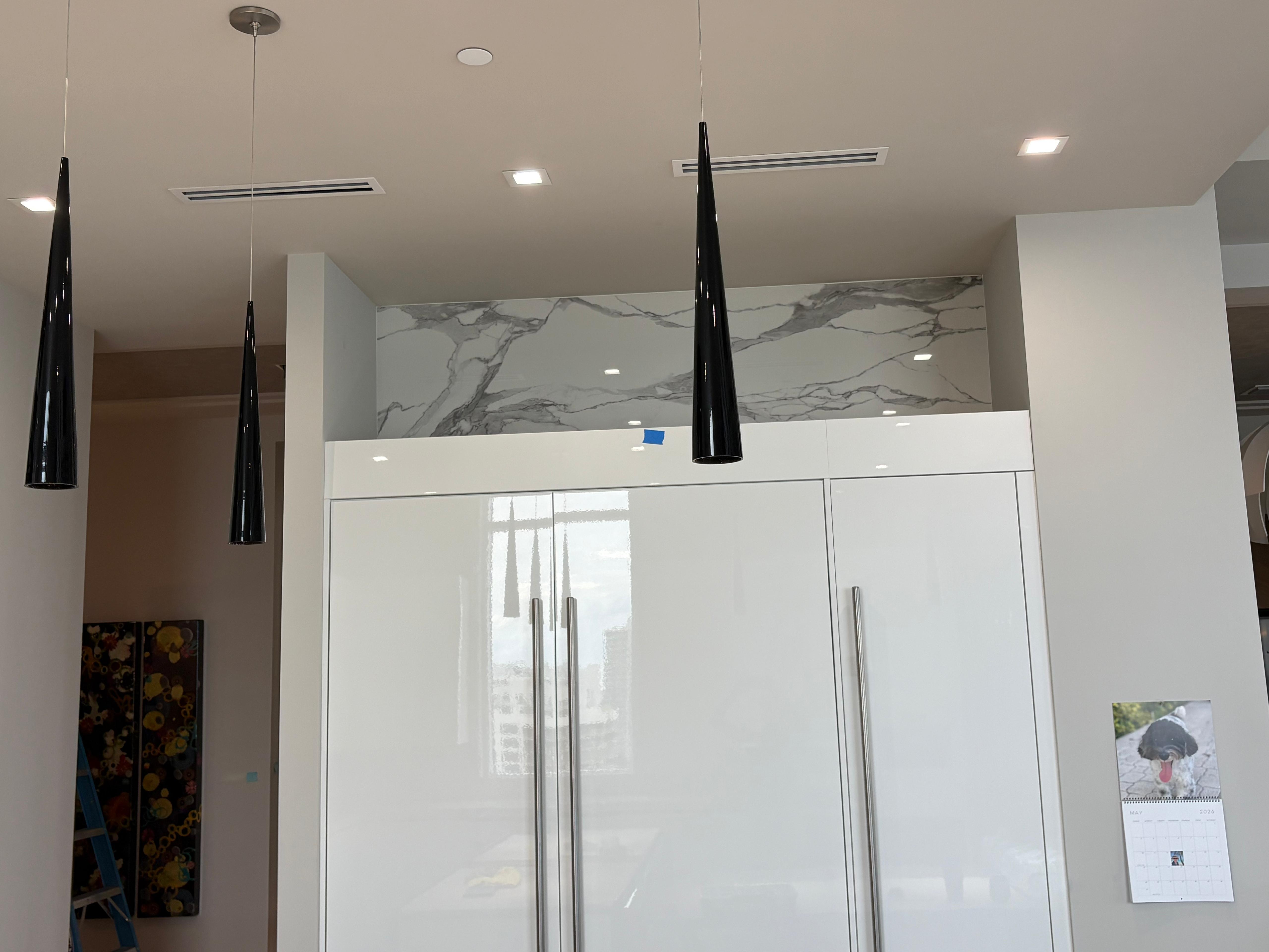 Handleless tall cabinets beneath a marble-look soffit